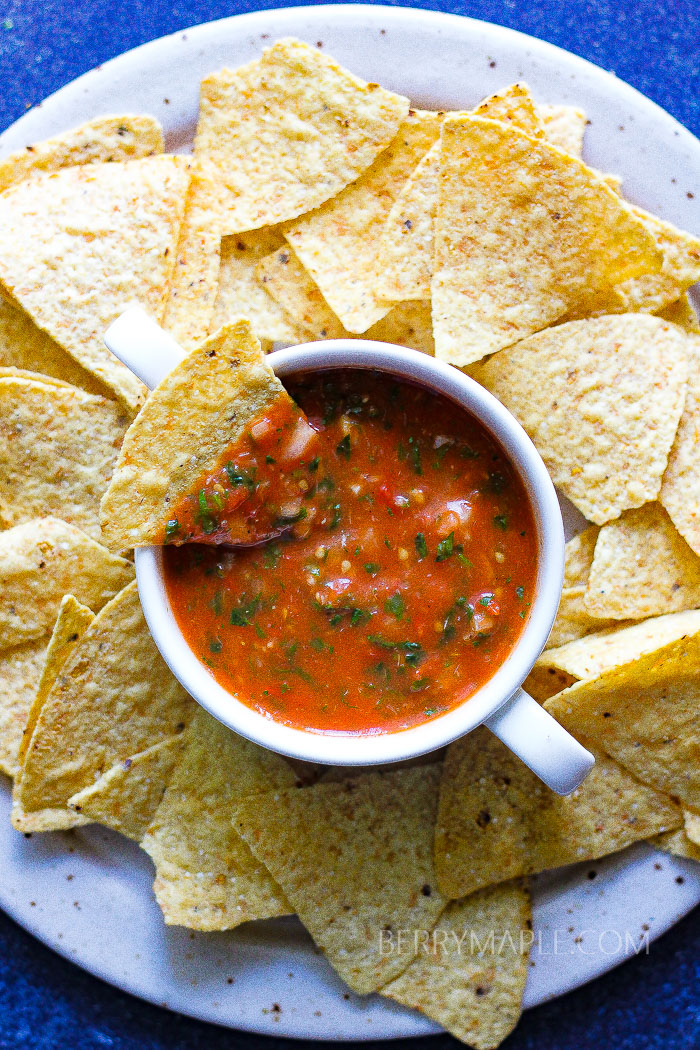 a plate full of corn chips and bowl of salsa