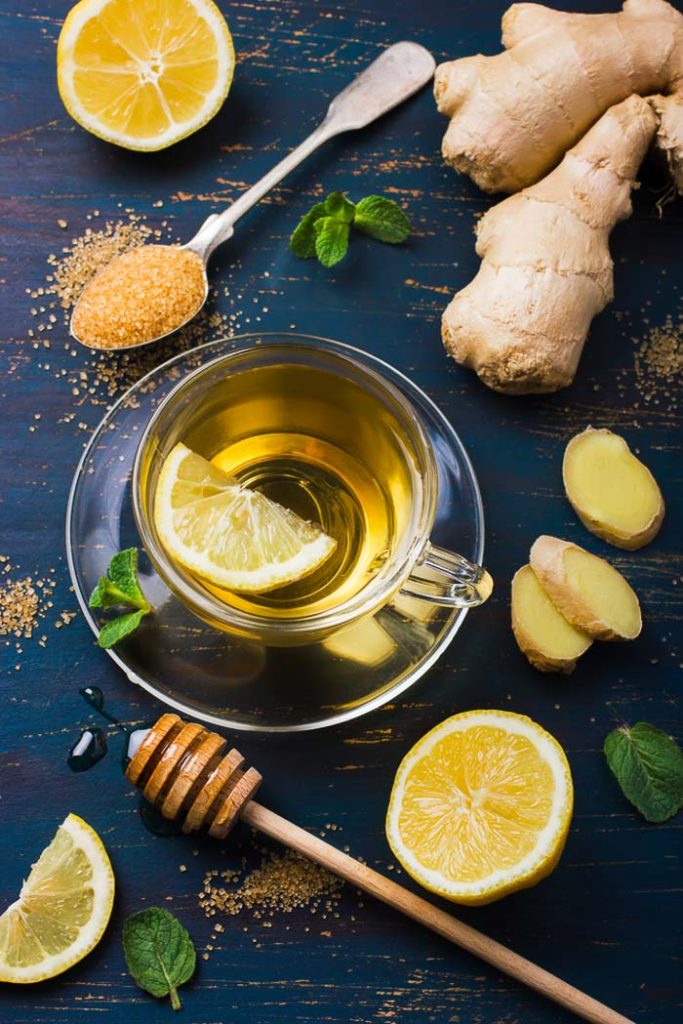 Cup of Ginger tea with lemon and honey on dark blue background, top view