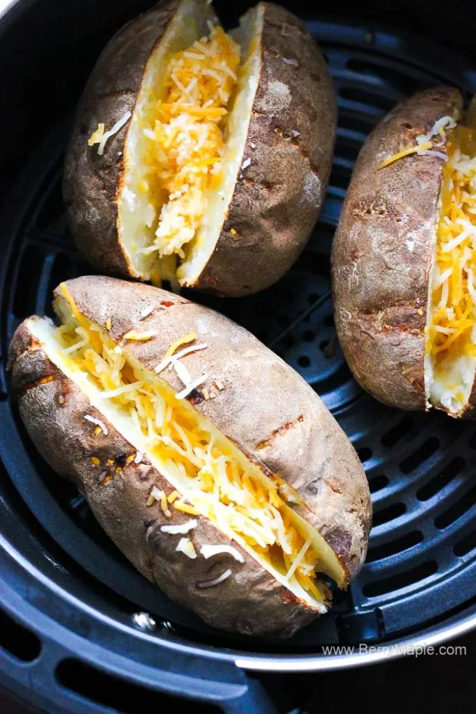 three potatoes with shredded cheese in air fryer