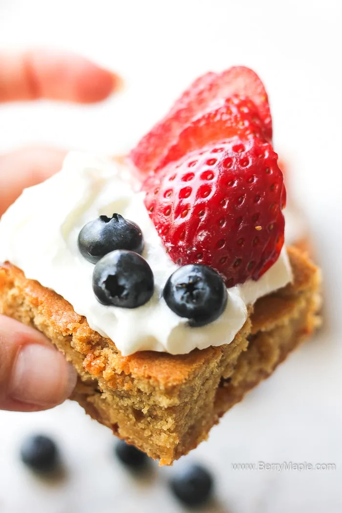 American flag colored patriotic dessert for your 4th of July BBQ party! Nice white chocolate blondies that are gooey, rich and very pretty! This chocolate bars are covered with whipped cream, juicy strawberries and blueberries. #4thofjuly #blondies blondie bars with berries