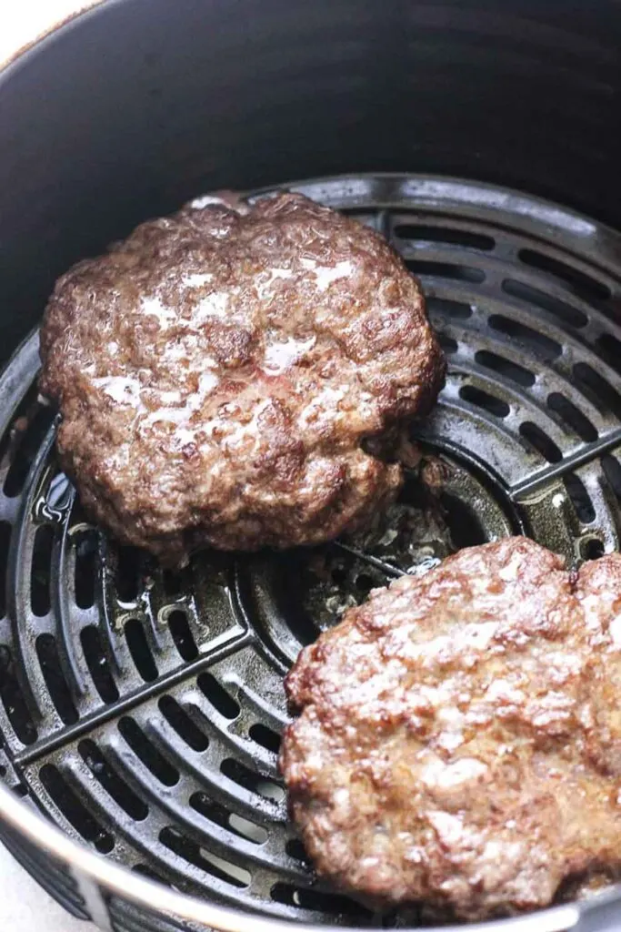 cooked burger patties in the air fryer basket