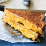 close shot of crunchy golden brown grilled cheese sandwich on a parchment paper