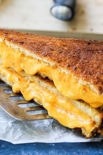 close shot of crunchy golden brown grilled cheese sandwich on a parchment paper