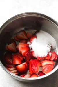 raw strawberry and sugar in a small pot