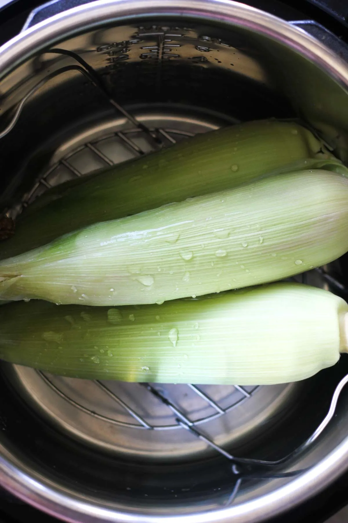 corn on the cob in husk in the instant pot inner pot with trivet