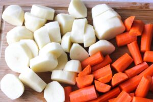 chopped raw potatoes and carrots on the brown cutting board