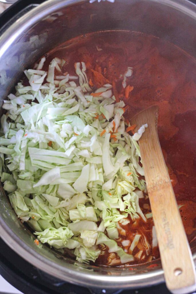 shredded cabbage in the pressure cooker on top of beef and onions