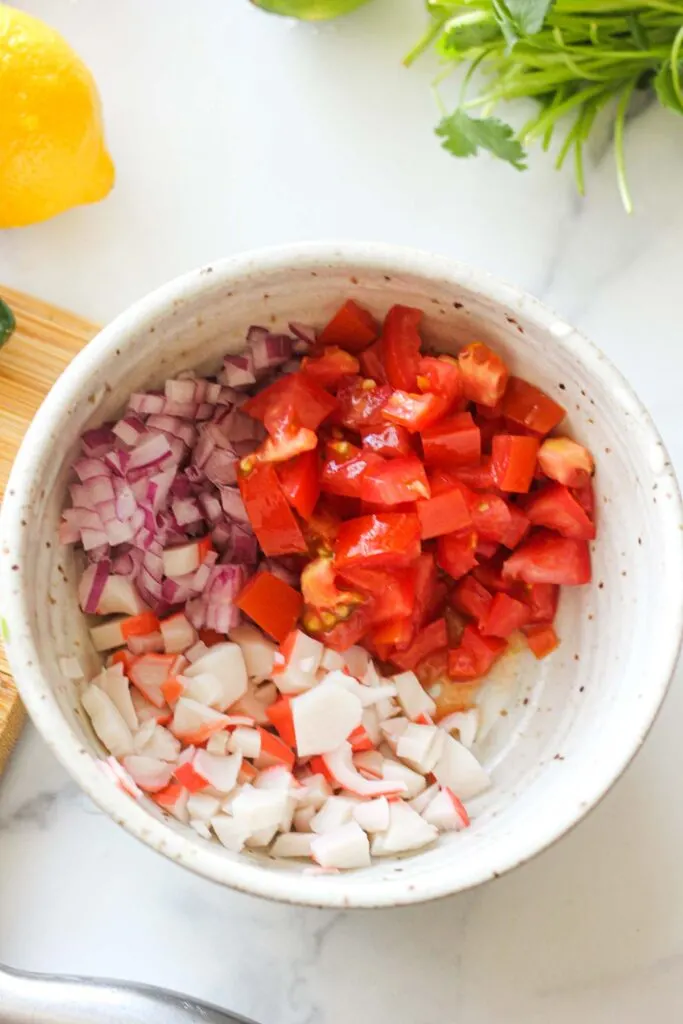 chopped tomatoes, crab and red onions in the bowl