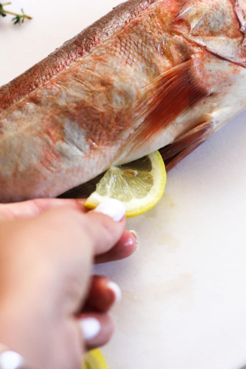 adding sliced lemon to the fish