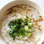 turkey congee in the bowl with chopped green onions and cilantro on top