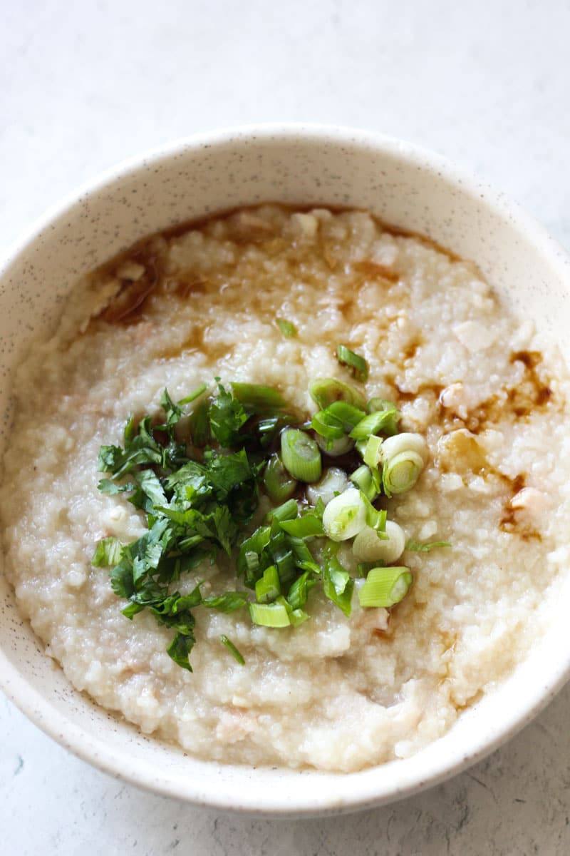 turkey congee in the bowl with chopped green onions and cilantro on top