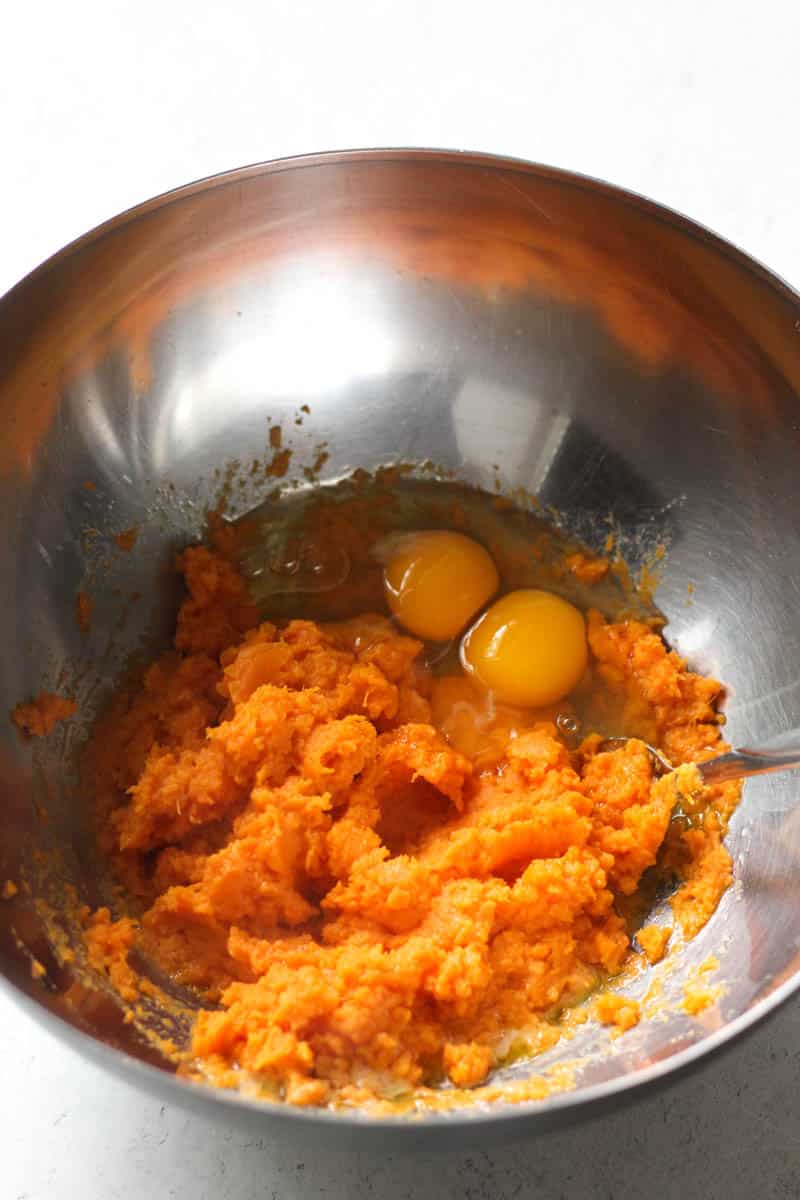 mashed sweet potatoes and two eggs in the metal bowl